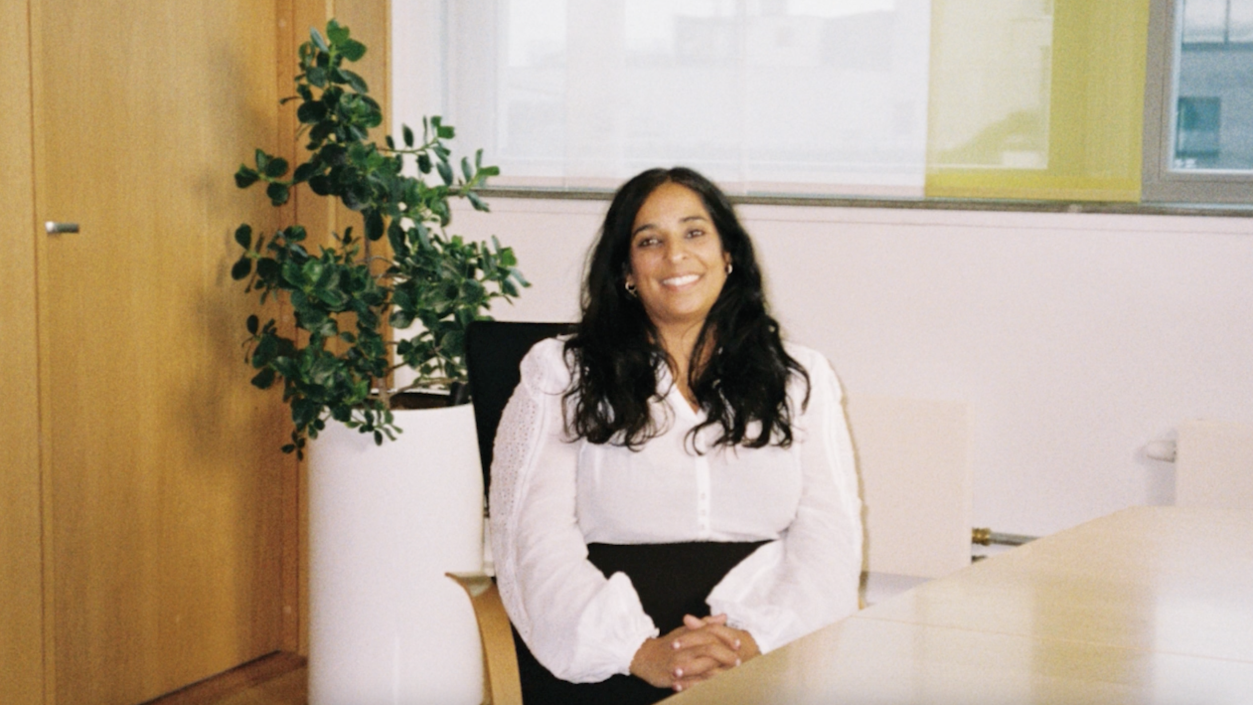 An analogue photo of Lubna Jaffery, Minister of Culture and Equality. She is smiling in an office setting.